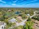 An aerial view of a community with homes near a pond and surrounded by many trees at 8367 Apple Orchard Rd, Spring Hill, FL 34608
