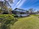 Lush backyard featuring a screened-in pool enclosure with a backdrop of mature trees at 8367 Apple Orchard Rd, Spring Hill, FL 34608