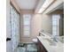 Bright bathroom featuring a shower, floral shower curtain, toilet, vanity, and large window at 8367 Apple Orchard Rd, Spring Hill, FL 34608