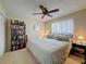 Comfortable bedroom featuring ceiling fan, a bookshelf, and a large window with sheer curtains at 8367 Apple Orchard Rd, Spring Hill, FL 34608