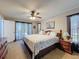 Cozy bedroom with large windows, a queen bed, ceiling fan, and dark wood furnishings at 8367 Apple Orchard Rd, Spring Hill, FL 34608