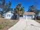 Charming single-story home featuring a blue exterior, a one-car garage, and a well-maintained front yard with a palm tree at 8501 Hunting Saddle Dr, Hudson, FL 34667