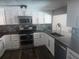 Modern kitchen with white cabinetry, stainless steel appliances, stylish backsplash, and beautiful wood-look flooring at 8501 Hunting Saddle Dr, Hudson, FL 34667