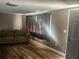 Cozy living room with wood-look floors, a patterned sofa, and a large window with curtains at 8501 Hunting Saddle Dr, Hudson, FL 34667