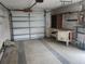 Spacious garage featuring work bench, storage shelving, and white garage door at 10803 Hachita Dr, Port Richey, FL 34668