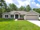 Charming single-story home with a well-manicured lawn, complemented by lush trees and a two-car garage at 11192 Kodiak Wren Rd, Weeki Wachee, FL 34614