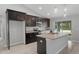 Modern kitchen features dark cabinets, stainless steel appliances, granite countertops and center island with sink at 11192 Kodiak Wren Rd, Weeki Wachee, FL 34614