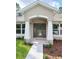 Close-up of the front door featuring decorative glass, white columns, and manicured landscaping at 11220 Sandpiper Ave, Weeki Wachee, FL 34614