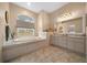 Bathroom featuring soaking tub with decorative tile surround, large window, and double vanity at 11298 Furley Ave, Weeki Wachee, FL 34613