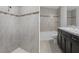 Bathroom with tiled shower and mosaic accents plus light gray stone-look tiling on floors and walls at 11388 Paramount Ave, Weeki Wachee, FL 34614