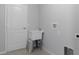 Functional laundry room equipped with gray walls, ceramic tile flooring, and a utility sink for convenience at 11388 Paramount Ave, Weeki Wachee, FL 34614