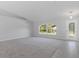 Spacious living room with gray carpet, arched window, and tiled entry leading to a decorative front door at 11388 Paramount Ave, Weeki Wachee, FL 34614