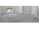 Expansive living area featuring gray carpeting, large windows, and an open layout leading to the kitchen at 11388 Paramount Ave, Weeki Wachee, FL 34614