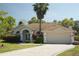 Attractive single-story home with landscaped yard, a two-car garage, and a beautiful palm tree at 11480 Emerald Ridge Ct, Spring Hill, FL 34609