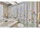 Well-lit bathroom with a floral shower curtain, a vanity with sink, toilet, and decorative wallpaper at 11526 Forest Run Ct, Port Richey, FL 34668