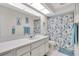 Bright bathroom with a single sink vanity, a large mirror, and a shower with a marine-themed curtain at 11526 Forest Run Ct, Port Richey, FL 34668