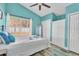 Bedroom with turquoise walls and ceiling fan features a closet and window view of backyard at 11526 Forest Run Ct, Port Richey, FL 34668