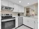 Bright kitchen with white cabinets, stainless steel appliances, and mosaic tile backsplash at 11526 Forest Run Ct, Port Richey, FL 34668