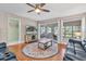 Cozy living room with a ceiling fan, a round area rug, hardwood floors, and a sliding door to the outside at 11526 Forest Run Ct, Port Richey, FL 34668
