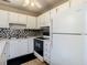 A kitchen with white cabinets, neutral backsplash, and featuring matching white appliances at 11917 Bayonet Ln # 11917, New Port Richey, FL 34654