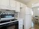 Well-lit kitchen boasts white cabinets and appliances, tile backsplash, and updated countertops at 11917 Bayonet Ln # 11917, New Port Richey, FL 34654