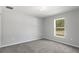 Bright bedroom featuring gray carpet, white walls, and a window providing natural light and a view at 13066 Nusser Ave, Weeki Wachee, FL 34614