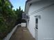 Side view of a white house featuring an exterior door, AC unit, and lush landscaping at 13610 Claudia Dr, Hudson, FL 34667