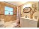 Cozy bathroom with tile walls, shower-tub combo, updated vanity, and decorative mirror at 13637 Allyn Dr, Hudson, FL 34667