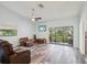 Spacious living room featuring wood floors, fan, and sliding glass doors leading to balcony at 1870 Whispering Way, Tarpon Springs, FL 34689