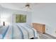 Bright bedroom with a ceiling fan, dresser and large window showing nature views at 3590 Magnolia Ridge Cir # 1103-C, Palm Harbor, FL 34684