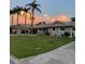 Well-maintained single-story home with a lush green lawn, swaying palm trees, and attached garage with sunset background at 3616 Harborview Ct, New Port Richey, FL 34652