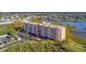 An aerial view of a pink waterfront condominium building with lovely landscaping and views of the bay at 4516 Seagull Dr # 408, New Port Richey, FL 34652