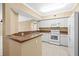 Kitchen with white appliances and cabinets, and tan countertops, with an eat in bar at 4516 Seagull Dr # 408, New Port Richey, FL 34652