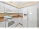 Galley kitchen with white appliances, tile floors, and light tan walls and trim at 4516 Seagull Dr # 408, New Port Richey, FL 34652