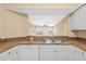 Galley style kitchen features white cabinets and appliances with a passthrough view of the living room at 4516 Seagull Dr # 408, New Port Richey, FL 34652