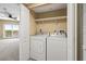 Convenient laundry closet with a washer and dryer unit and shelving for storage, in hall near Primary bedroom at 4516 Seagull Dr # 408, New Port Richey, FL 34652