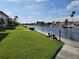 Scenic waterfront view featuring lush green grass, sidewalk, and dock with boat parking at 4715 Jasper Dr # 105, New Port Richey, FL 34652