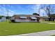 Well-kept single-story home with a vibrant green lawn, covered parking, and brick accents at 4938 Azalea Dr, New Port Richey, FL 34652