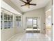 Bright sunroom with white tile flooring, multiple windows, and sliding door access to the screened lanai at 4974 Harbor Woods Dr, Palm Harbor, FL 34683