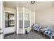 Charming front porch featuring tile flooring, decorative window, and cozy white wicker chairs with blue and white cushions at 6518 Remus Dr, New Port Richey, FL 34653