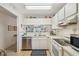 Well-lit kitchen featuring white appliances and cabinetry, with an adjacent dining area at 6518 Remus Dr, New Port Richey, FL 34653