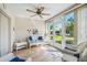 Bright sunroom featuring wood floors, ceiling fan, and comfortable wicker furniture with blue cushions overlooking the yard at 6518 Remus Dr, New Port Richey, FL 34653