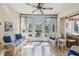 Bright sunroom featuring wood floors, ceiling fan, and comfortable wicker furniture with blue cushions overlooking the yard at 6518 Remus Dr, New Port Richey, FL 34653