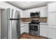 Bright kitchen with stainless steel appliances and white cabinets, featuring modern fixtures and ample counter space at 7083 Devlin St, Weeki Wachee, FL 34613