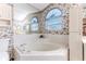Bathroom featuring a luxurious corner tub, floral wallpaper, and ample natural light from arched windows at 9131 Rhett Ln, Weeki Wachee, FL 34613