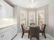 Bright breakfast nook with white cabinetry, a ceiling fan, and a large bay window overlooking the greenery at 9144 Bassett Ln, New Port Richey, FL 34655