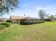 Well-maintained home exterior showcasing a spacious, green backyard, mature shrubbery, and a screened-in lanai at 9630 Southern Belle Dr, Weeki Wachee, FL 34613