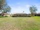 Wide-angle view of expansive lawn, mature trees, and the home's screened-in patio at 9630 Southern Belle Dr, Weeki Wachee, FL 34613