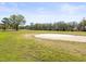 Scenic view of a lush, green golf course with mature trees and a pristine sand trap at 9630 Southern Belle Dr, Weeki Wachee, FL 34613