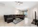 Cozy living room features a comfortable leather sectional, a ceiling fan, and sliding doors to the patio at 11023 Silver Dancer Dr, Riverview, FL 33579